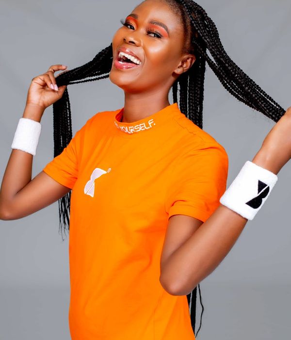 A smiling woman in sportswear feeling energetic and positive in a bright studio.